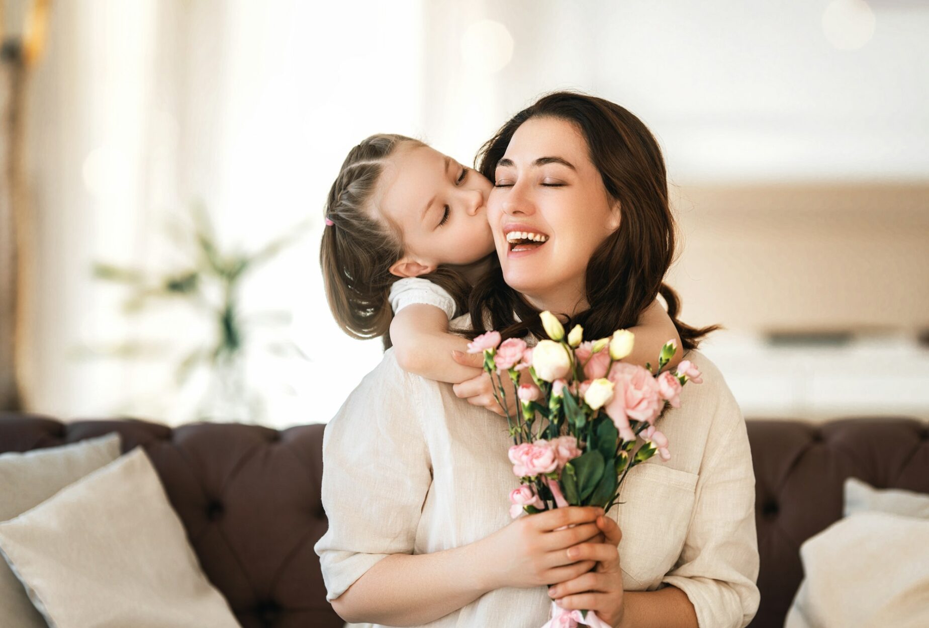 Daughter giving mother bouquet of flowers.